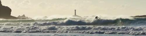 This is a landscape photograph taken at Sennen Cove on the coast of the United Kingdom during a late autumn afternoon. The image shows a surfer riding the sea waves in the region known as Surfing Longships Wide, with the water reflecting the soft light typical of this time of day in autumn. In the distance, the Longships Lighthouse rises above the rugged coastal scenery, acting as a landmark against the cloudy sky. The natural elements—including the rolling waves, the mist above the sea, and rocky outcrops—create an authentic portrayal of nature, highlighting the dynamic relationship between the sea and the coast in this part of the United Kingdom.